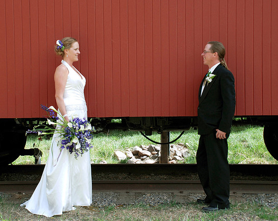 bride and groom posing in front of caboose